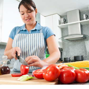 A woman chopping vegetables in a bright kitchen.