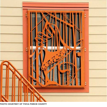 A window covered with a decorative metal grate that doubles as a secure cover