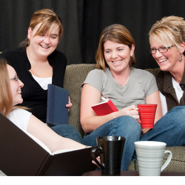 Four women gathered around a coffee table smiling.