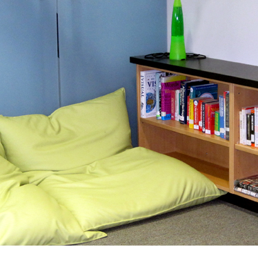 A reading nook with small bookshelf and pillows on the floor for sitting.
