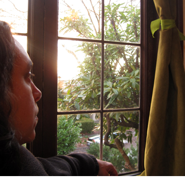 A woman looking out of a window as the sun sets.